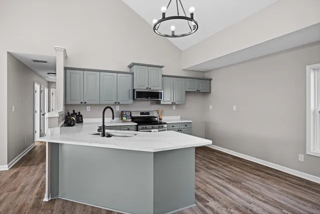 a kitchen with stainless steel appliances a sink stove and wooden floor