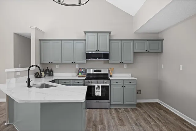 a kitchen with a sink dishwasher a stove a microwave oven a refrigerator with white cabinets and wooden floor