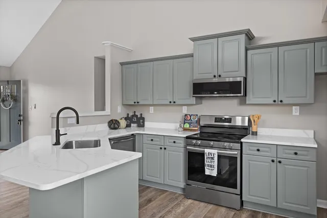 a kitchen with stainless steel appliances granite countertop a sink dishwasher a microwave oven and a dining table with wooden floor