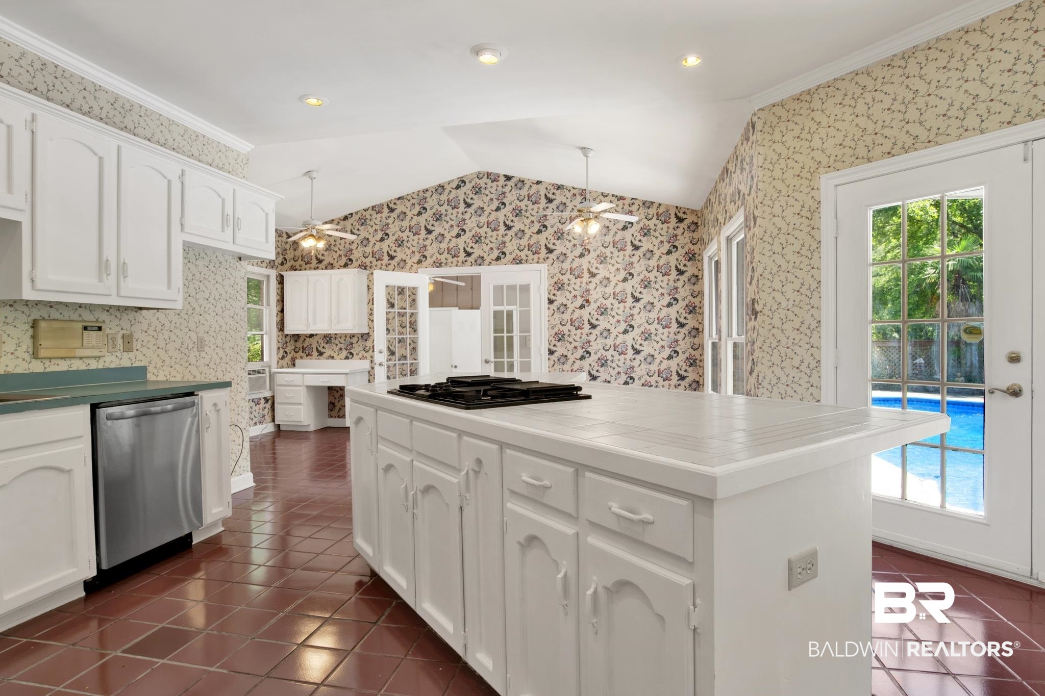 6805 Hunters Court Mobile, AL 36695 - Photo 14 of 37 Kitchen with dishwasher, dark tile patterned flooring, vaulted ceiling, wallpapered walls, and black gas cooktop