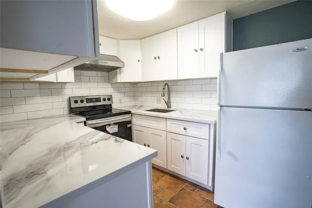 a kitchen with granite countertop white cabinets and white appliances