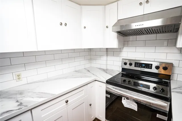 a kitchen with white cabinets and appliances