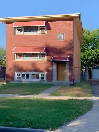 a view of a big building with a big yard and large trees