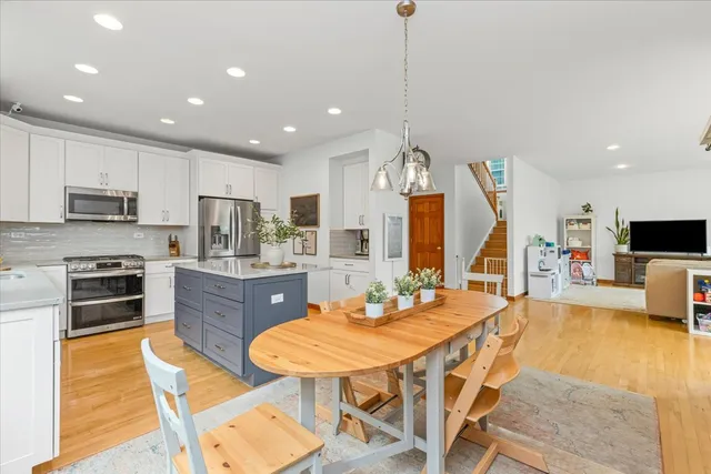 a large kitchen with stainless steel appliances kitchen island granite countertop a sink a stove a dining table and chairs