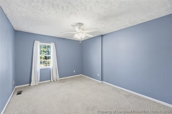 an empty room with windows and fan