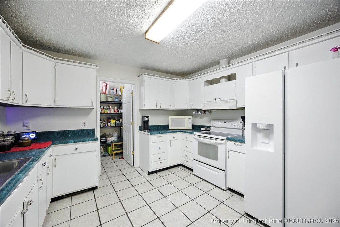 223 Broadwell Road St. Pauls, NC 28384 - Photo 16 of 28 a kitchen with granite countertop white cabinets and white appliances