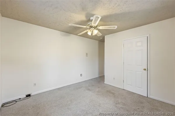 an empty room with a fan & a ceiling fan