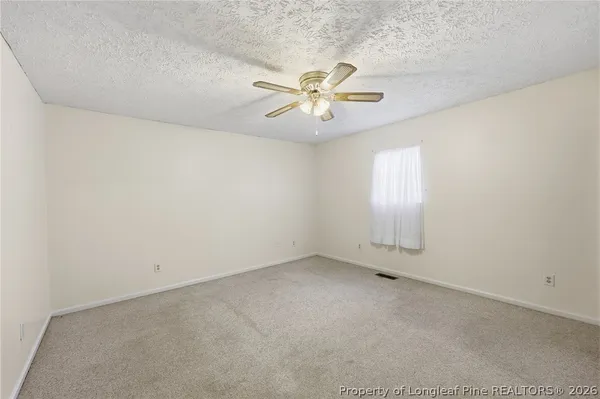 an empty room with a window and a fan