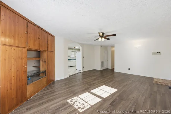 an empty room with wooden floor closet and windows