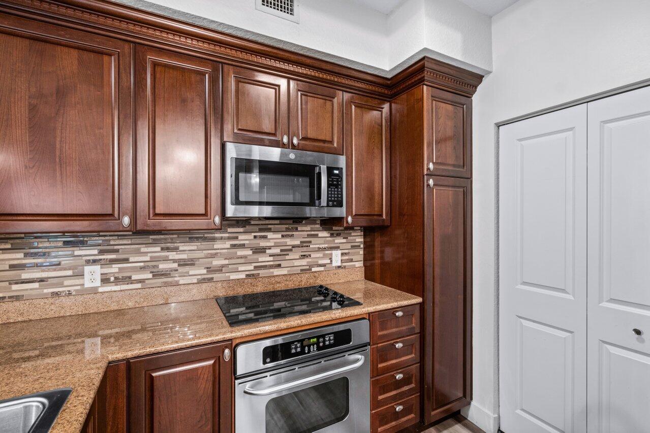 1117 Renaissance Way, Unit 117 Boynton Beach, FL 33426 - Photo 11 of 31 a kitchen with granite countertop a stove and a microwave