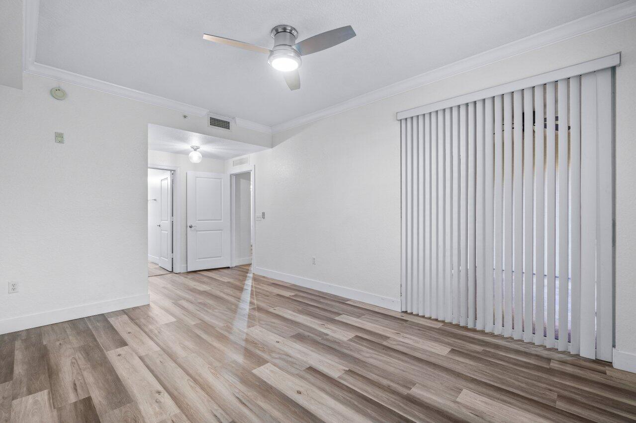 1117 Renaissance Way, Unit 117 Boynton Beach, FL 33426 - Photo 22 of 31 an empty room with wooden floor fan and windows