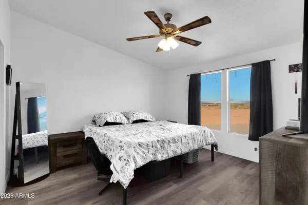 a bedroom with a bed a large window with wooden floor
