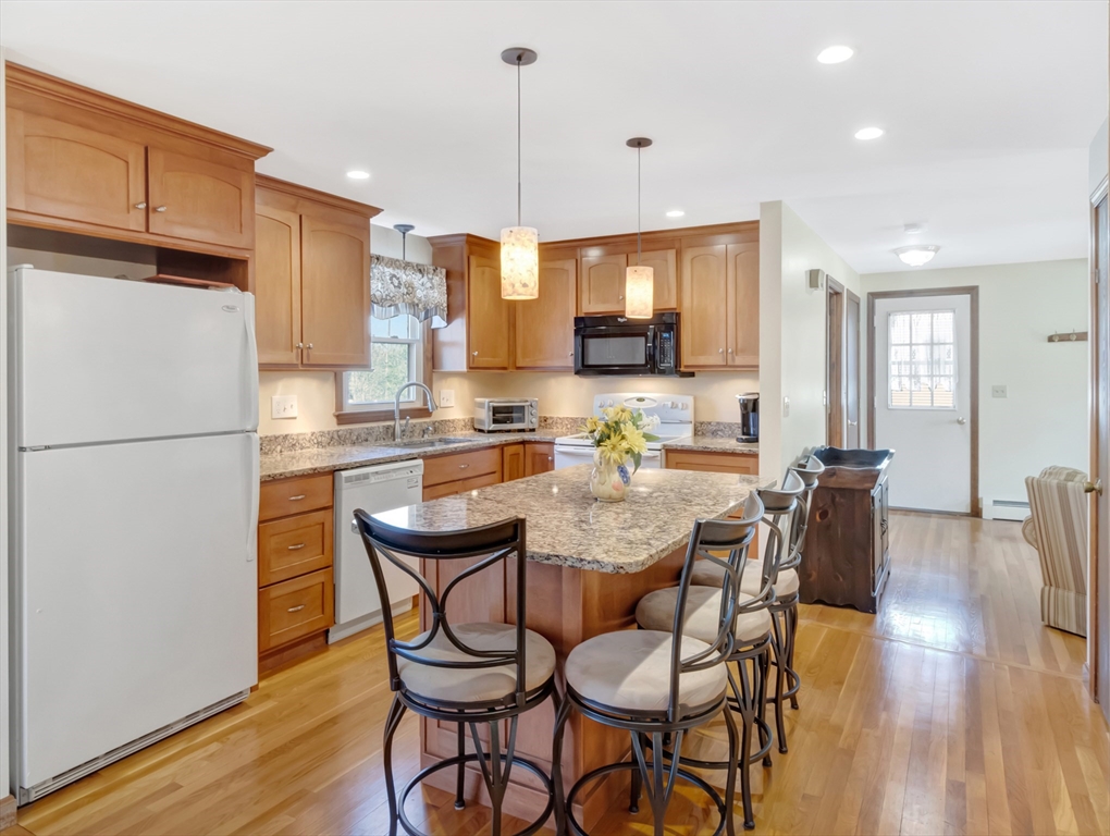 15 Riverside Drive Mansfield, MA 02048 - Photo 6 of 42 a kitchen with stainless steel appliances kitchen island granite countertop a refrigerator a stove a microwave oven a dining table and chairs with wooden floor