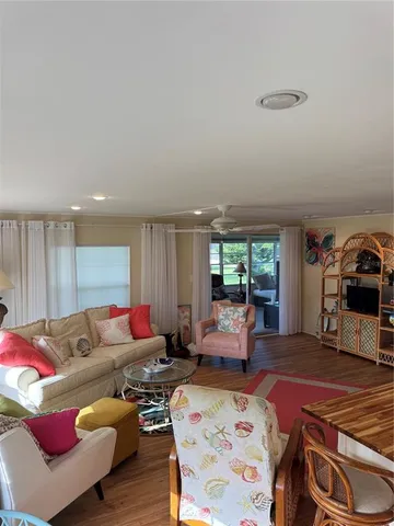 a kitchen with granite countertop a refrigerator a sink dishwasher a stove and white cabinets with wooden floor