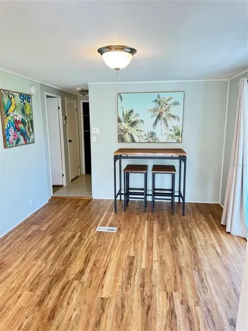a bedroom with a bed and dresser with wooden floor
