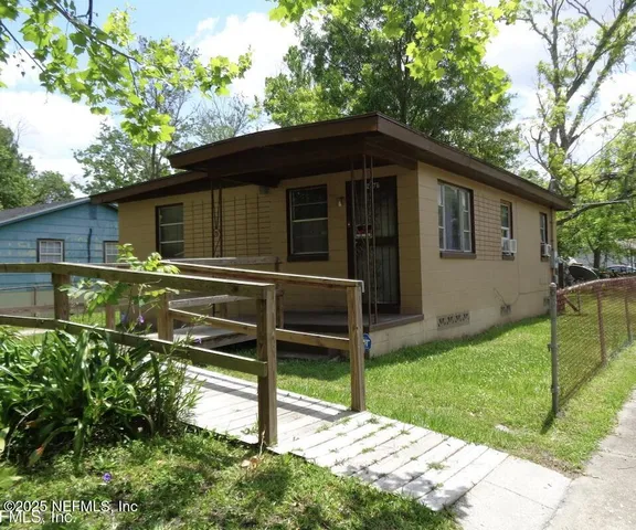 a backyard of a house with plants and large tree