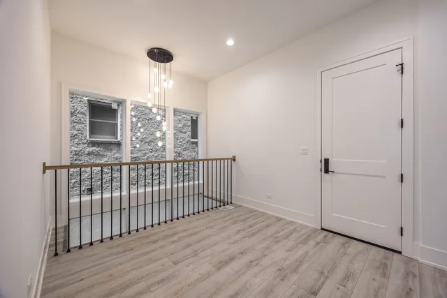 a view of a hallway with wooden floor and chandelier