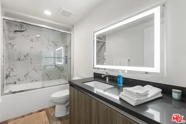 a bathroom with a granite countertop sink mirror toilet and bathtub