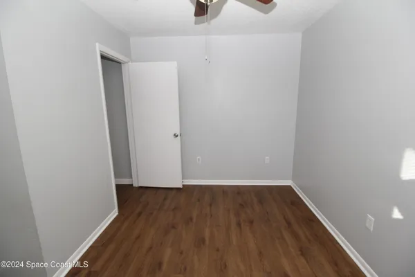 an empty room with wooden floor cabinet and windows
