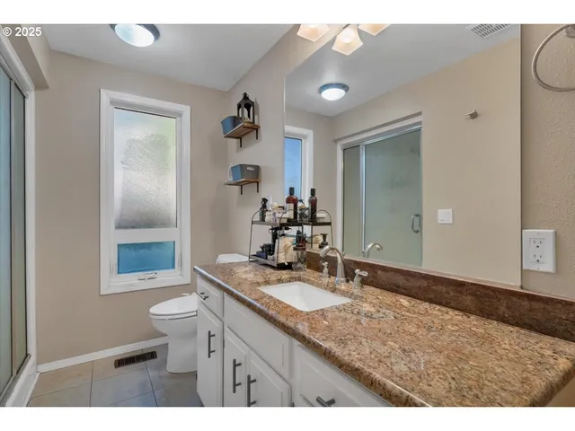a bathroom with a granite countertop sink a mirror and a toilet