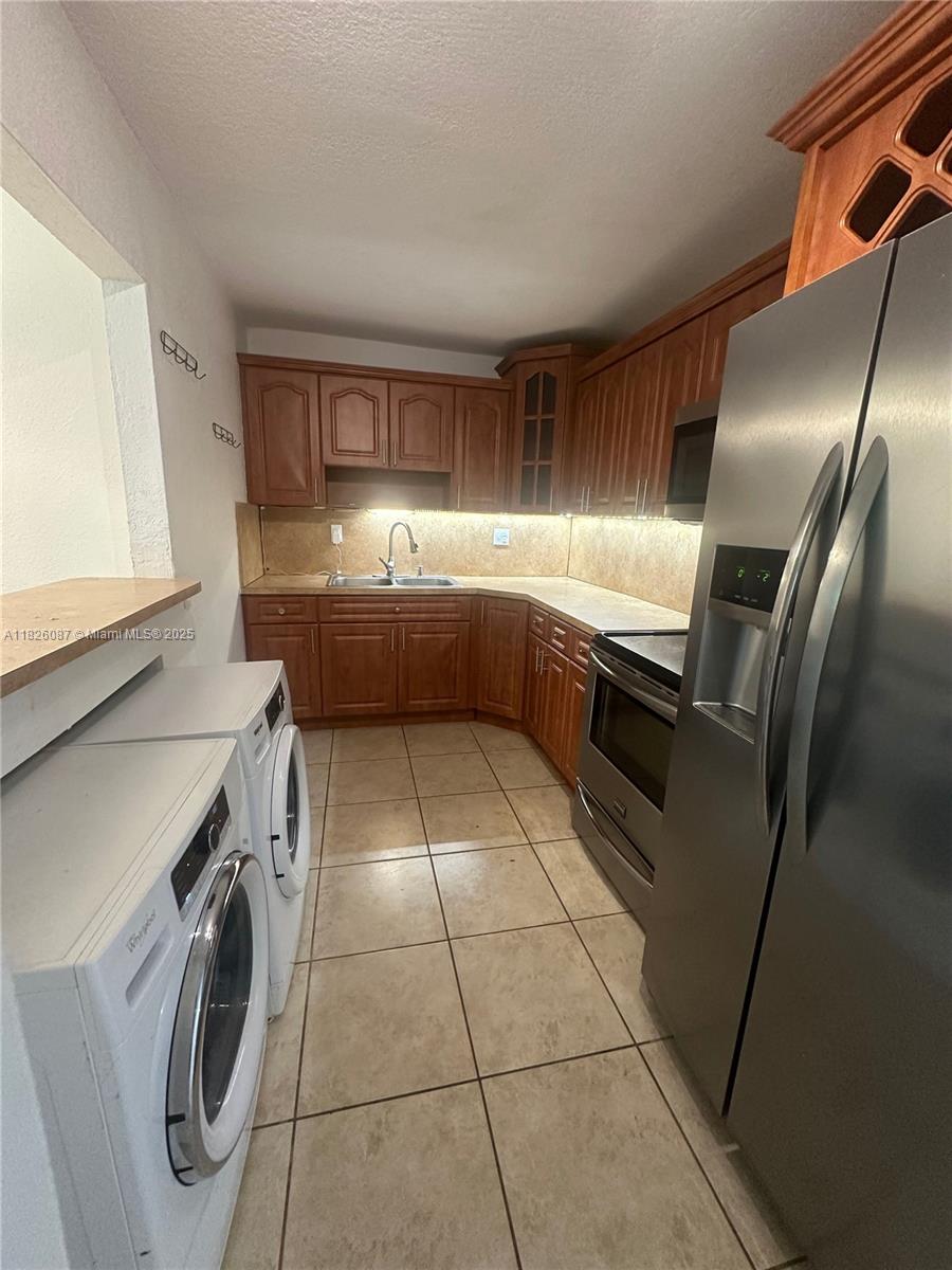 9487 Southwest 76th Street, Unit M8 Miami, FL 33173 - Photo 6 of 16 a kitchen with granite countertop a sink a washer and dryer