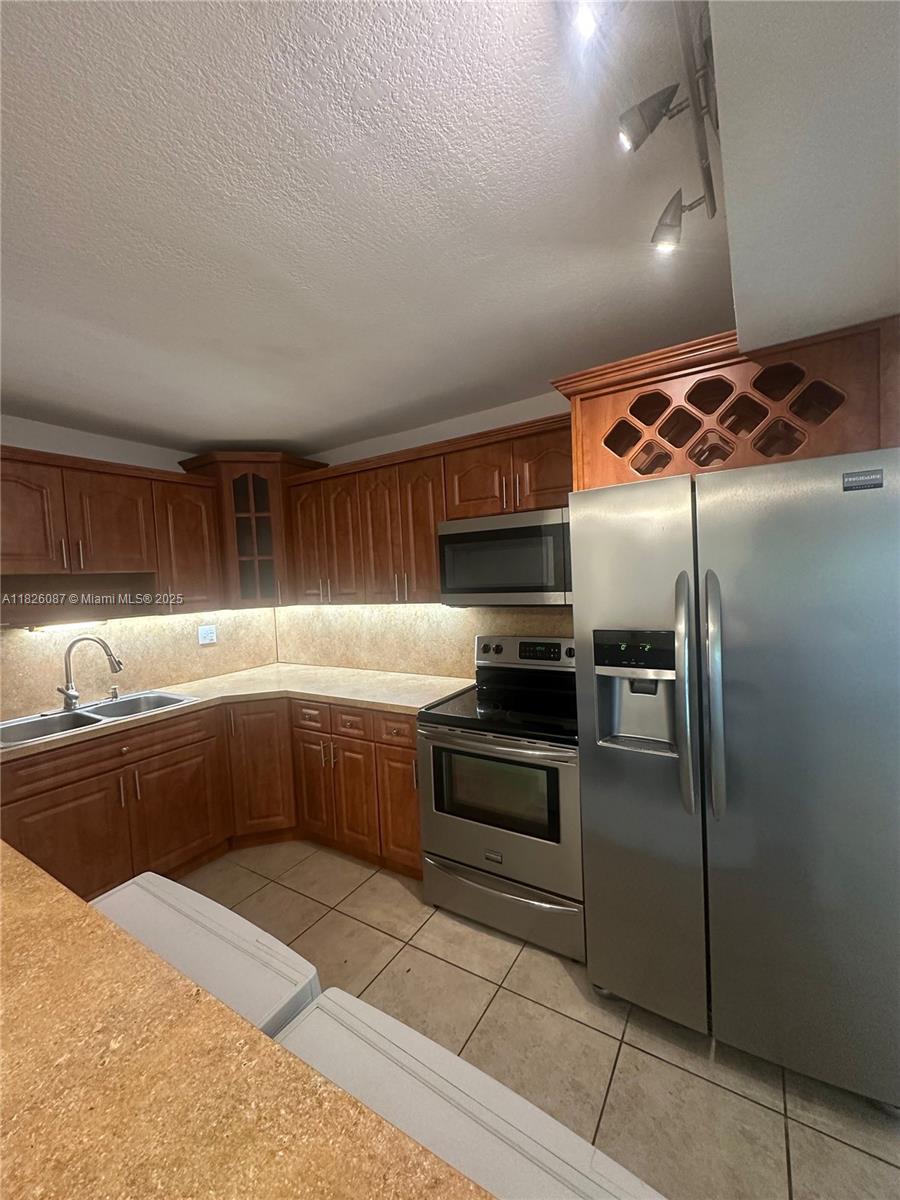 9487 Southwest 76th Street, Unit M8 Miami, FL 33173 - Photo 7 of 16 a kitchen with granite countertop a refrigerator and a sink