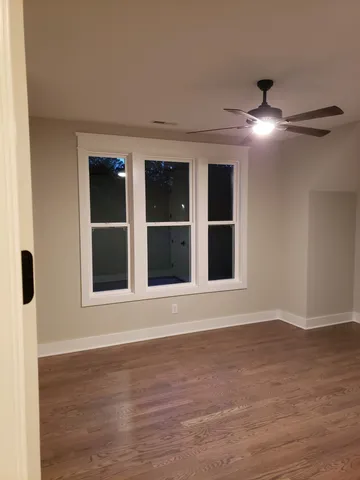 a view of an empty room with wooden floor and windows