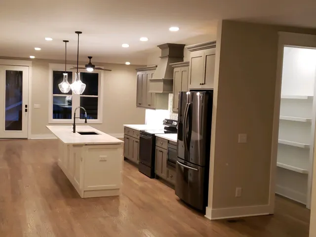 a kitchen with stainless steel appliances kitchen island granite countertop a refrigerator a sink a stove and oven