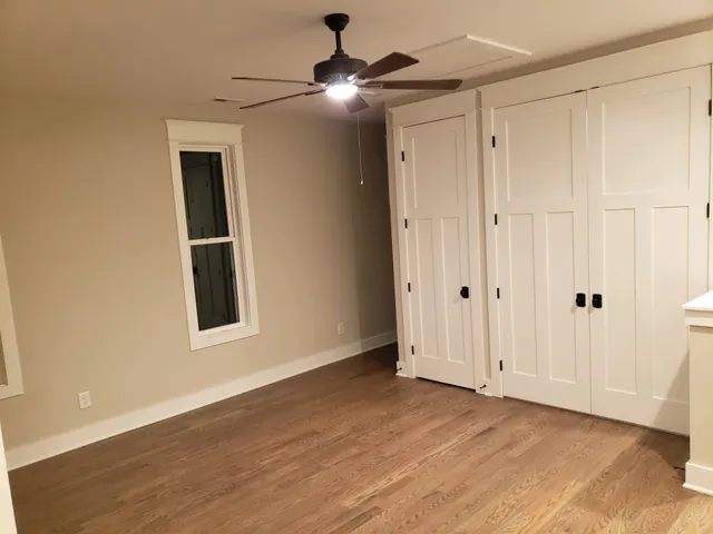 a view of an empty room with window and chandelier fan