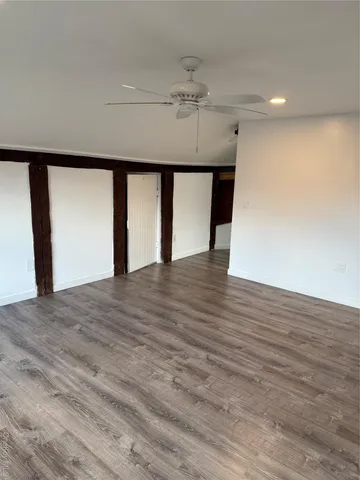 a view of an empty room with wooden floor and chandelier
