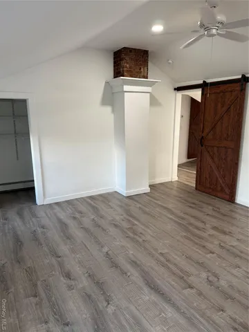 an empty room with wooden floor and a ceiling fan