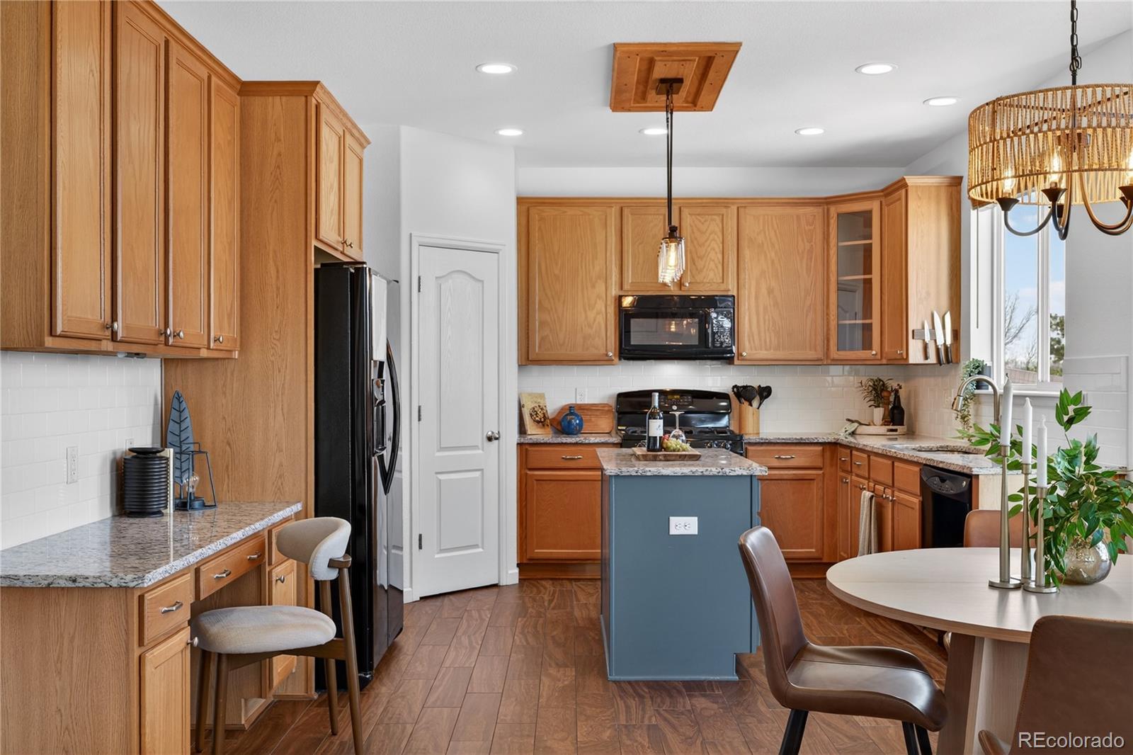 10180 Audrey Street Firestone, CO 80504 - Photo 14 of 46 a kitchen with stainless steel appliances granite countertop a refrigerator a stove a sink a dining table and chairs with wooden floor