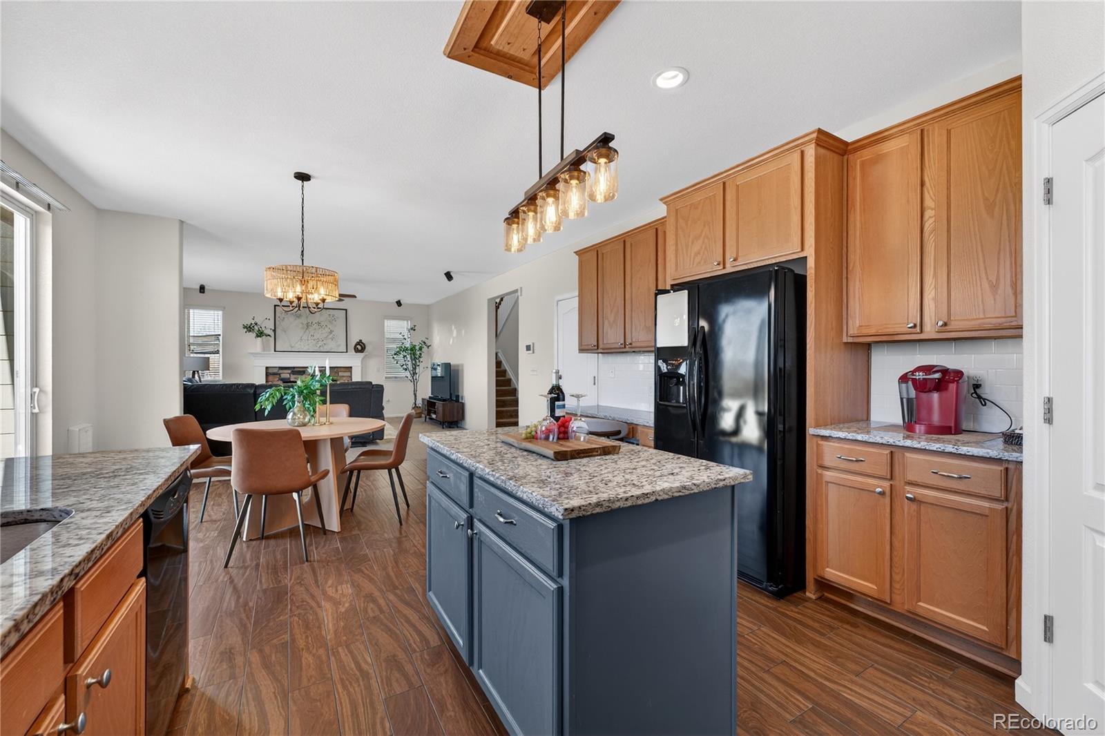 10180 Audrey Street Firestone, CO 80504 - Photo 18 of 46 a kitchen with a refrigerator a stove top oven a sink dishwasher and a dining table with wooden floor