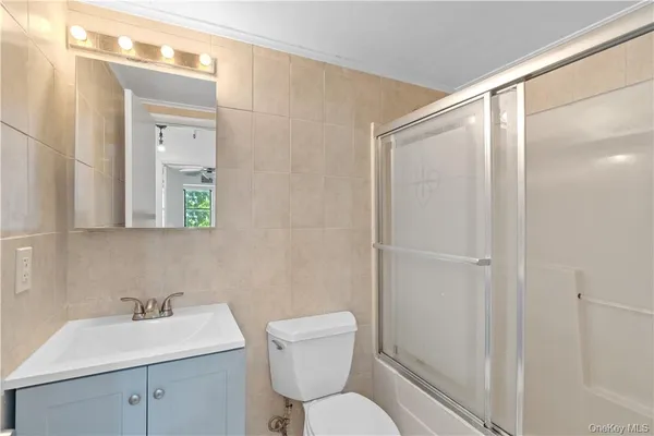 a bathroom with a toilet a sink a mirror a vanity and shower