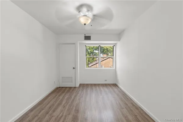 an empty room with wooden floor chandelier fan and windows