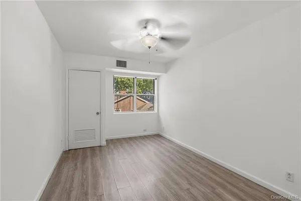 an empty room with wooden floor chandelier and windows