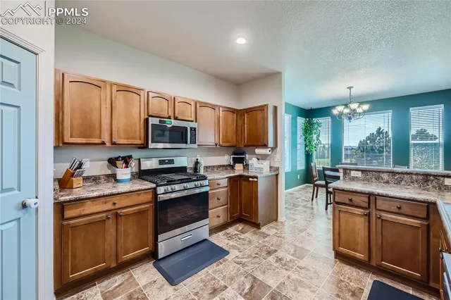 a kitchen with stainless steel appliances granite countertop a stove top oven a sink dishwasher a dining table and chairs with wooden floor