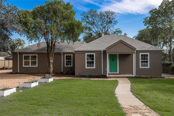 a front view of a house with a yard and trees