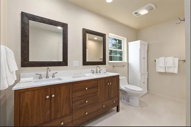 a bathroom with double vanity sink a mirror and a toilet