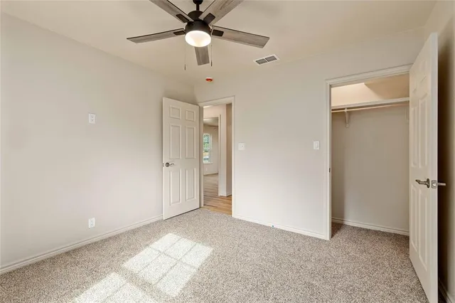an empty room with a ceiling fan and a window