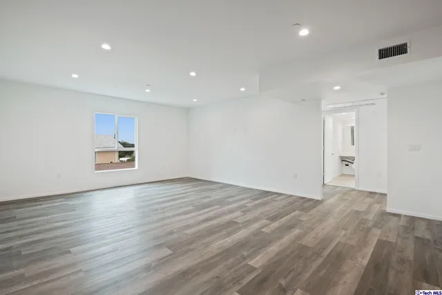 a view of an empty room with wooden floor and window