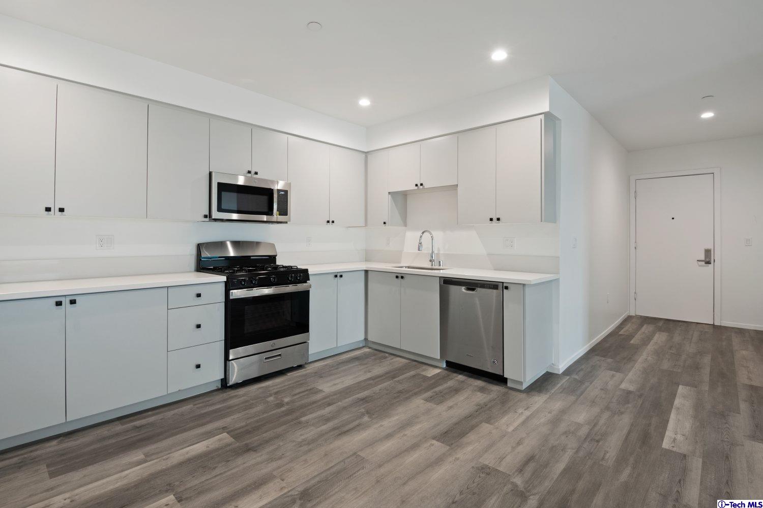 7064 Greeley Street, Unit 101 Tujunga, CA 91042 - Photo 20 of 37 a kitchen with kitchen island white cabinets stainless steel appliances and sink