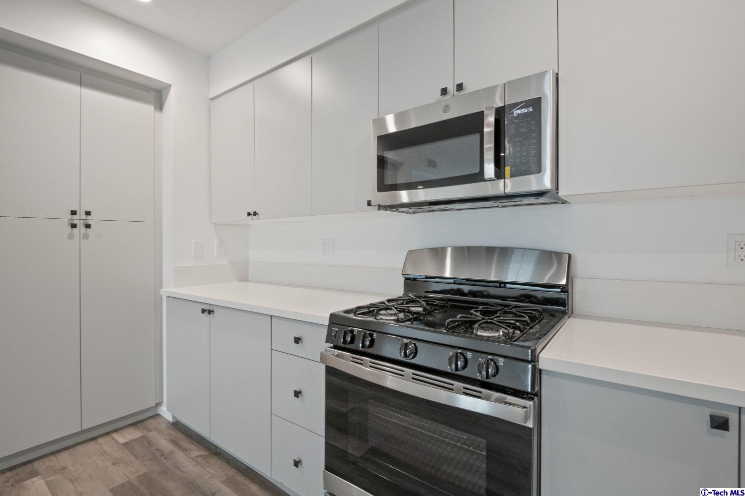 7064 Greeley Street, Unit 101 Tujunga, CA 91042 - Photo 23 of 37 a kitchen with cabinets stainless steel appliances and a wooden floor
