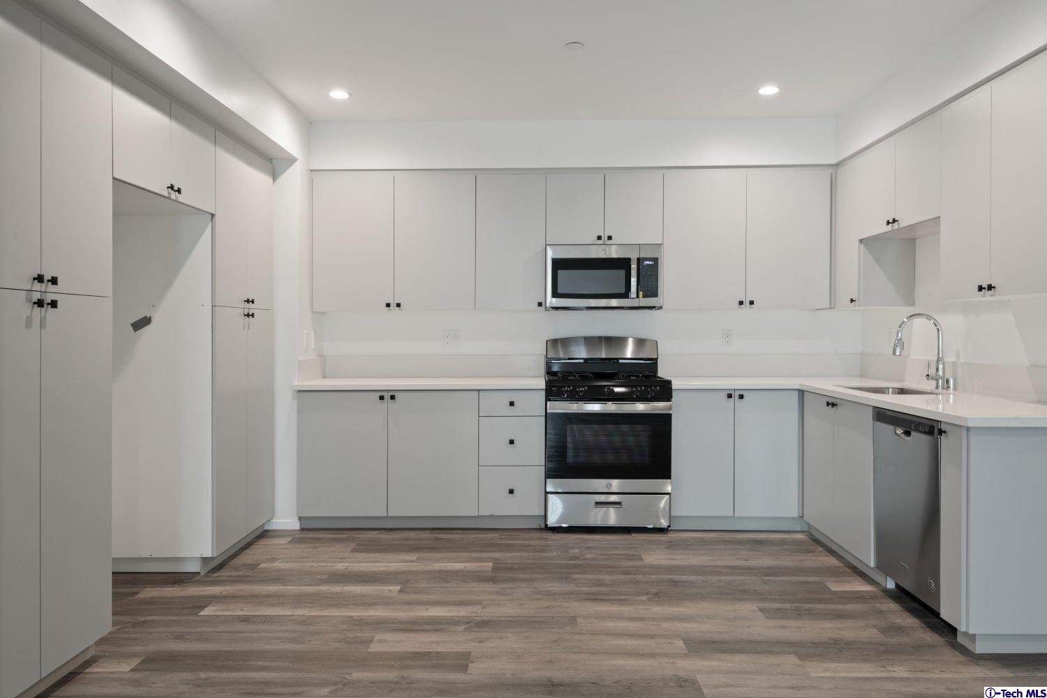 7064 Greeley Street, Unit 101 Tujunga, CA 91042 - Photo 24 of 37 a kitchen with kitchen island white cabinets appliances and a sink