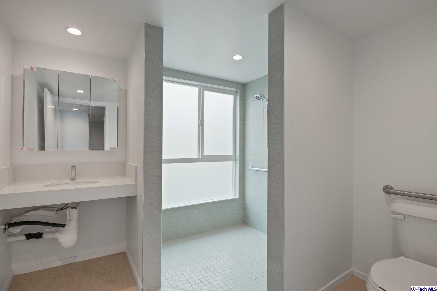 7064 Greeley Street, Unit 101 Tujunga, CA 91042 - Photo 28 of 37 a bathroom with a toilet sink a mirror and vanity