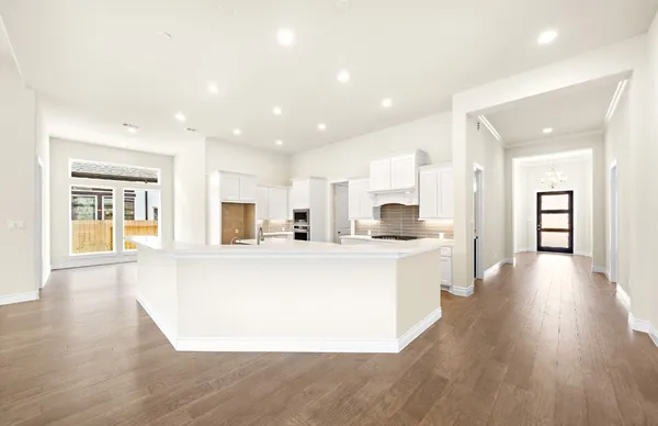 a large white kitchen with wooden floors and view living room