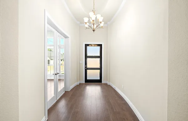 a view of a hallway with wooden floor and a chandelier