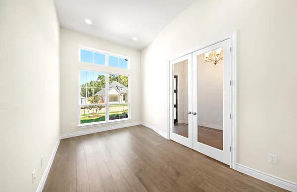 an empty room with wooden floor and windows