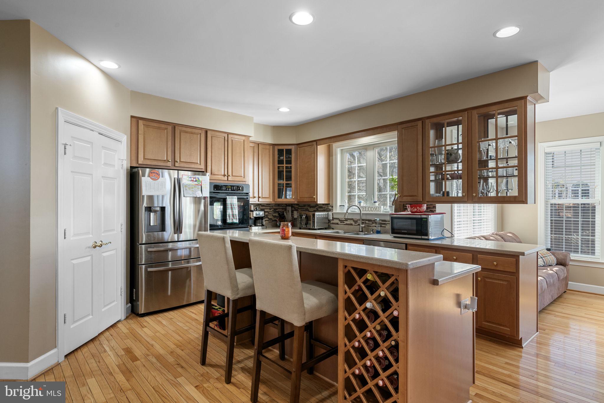 4016 Sapling Way Triangle, VA 22172 - Photo 14 of 56 a kitchen with stainless steel appliances granite countertop a stove a refrigerator a sink a dining table and chairs with wooden floor
