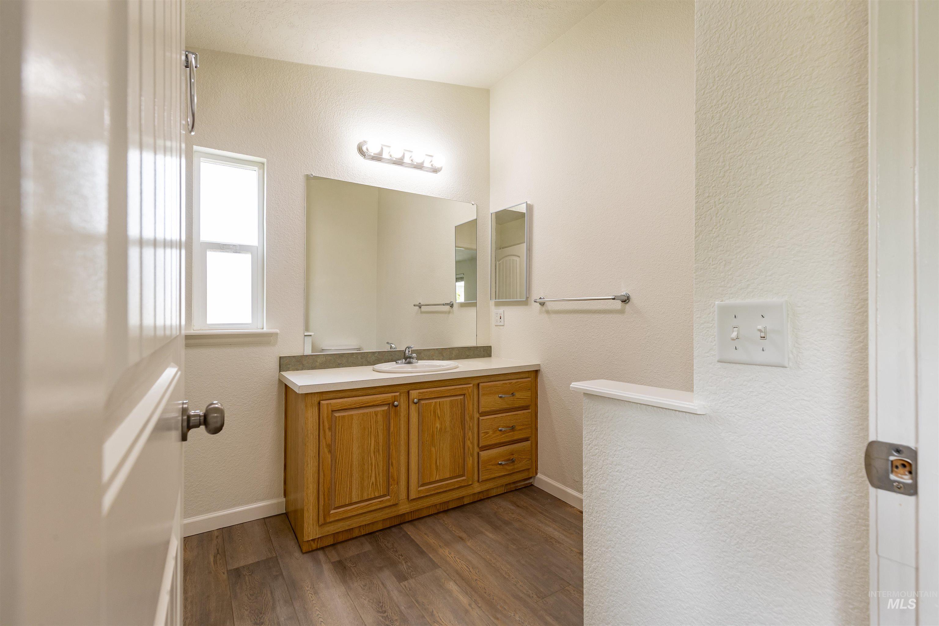 17028 Lower Pleasant Ridge Road Caldwell, ID 83607 - Photo 10 of 21 Bathroom vanity featuring light wood cabinetry, a built-in sink, and a light-colored countertop